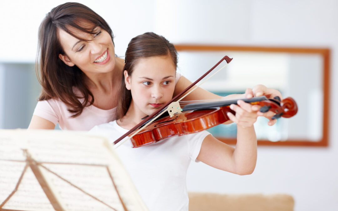A mother helping her young daughter hold a beginner violin properly during home practice.